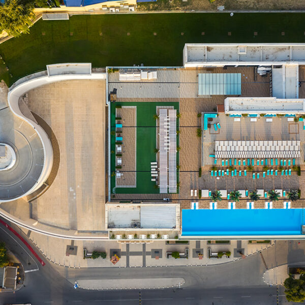 Top view of an empty hotel swimming pool at the roof of the building in a sea resort. Drone photography.